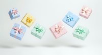 Colorful gift boxes with bows floating on white background, isolated presents in pastel pink, blue, yellow and green for holiday celebrations, birthdays and special occasions.