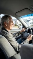 Happy senior Caucasian man driving car smiling while holding steering wheel in vehicle interior for transportation and mobility concepts.