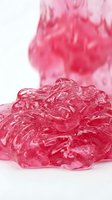 Vibrant pink translucent slime with glossy texture stretches and flows against white background, ideal for creative projects and design applications.