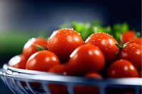 Fresh cherry tomatoes with water drops in blue ceramic bowl against dark background, macro shot highlighting natural texture and vibrant red color.