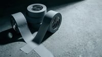 Industrial duct tape rolls in monochrome styling on concrete surface for construction and repair projects with dramatic lighting effects.