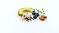 Fresh avocado half with blueberries, almonds and chia seeds on white background. Healthy superfood ingredients for ketogenic diet and clean eating.