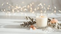 Cozy white candle burning with eucalyptus leaves and warm bokeh lights creating peaceful spa atmosphere for relaxation and wellness.