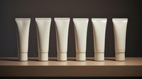 White cosmetic tubes arranged in row on wooden surface against dark background, minimalist product presentation for beauty and skincare packaging mockup.