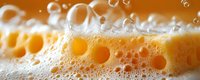 Macro shot of beer foam and bubbles with golden amber liquid showing detailed texture and effervescence in extreme closeup. Perfect for beverage industry.