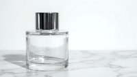 Clear glass perfume bottle with silver cap on white marble surface for luxury cosmetics and fragrance branding.