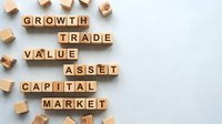 Wooden letter cubes spelling financial terms growth, trade, value, asset, capital, market on light background, finance and investment concept.