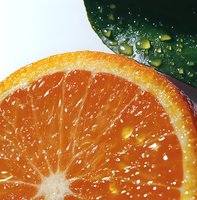 Fresh juicy orange slice with water droplets and green leaf in macro shot, vibrant citrus fruit texture showing detailed pulp segments and peel for healthy food concept.
