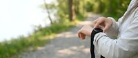 Man in white shirt checking empty wallet on outdoor path with green foliage background, depicting financial hardship and money problems.