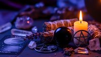 Mystical fortune telling setup with crystal ball, tarot cards, candle and pentagram symbol for divination and spiritual guidance sessions.