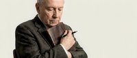 Senior Caucasian man in olive blazer holding pen, contemplative pose for business, education, and professional concepts.