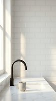 Minimalist bathroom sink with black faucet and white ceramic cup on marble countertop, bright natural light from window, white subway tile wall background.