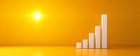 Growing white bar graph chart showing upward trend against vibrant golden yellow background with glowing sun, symbolizing success and financial growth progress.