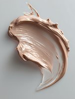Creamy beige foundation or concealer cosmetic product smear texture with dynamic swirl motion on light gray background, isolated makeup swatch for beauty industry.
