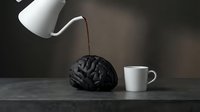 Pouring water into black brain sculpture with white mug on dark surface, creative conceptual still life for advertising and design projects.