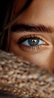 Close-up of bright blue eye with long eyelashes and defined eyebrow. Warm skin tone and natural makeup create soft glamour look for beauty and cosmetic advertising.