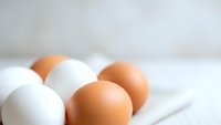 Fresh brown and white chicken eggs arranged on marble surface for cooking and baking recipes in modern kitchen setting.