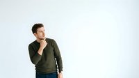 Thoughtful man in olive green sweatshirt touching chin, looking away with contemplative expression against white background for business and lifestyle concepts.