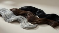 Natural hair extensions in black brown and silver gray colors flowing waves for beauty salon hairdressing and styling applications.
