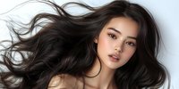 Young Asian woman with flowing dark hair against light background, natural makeup, glowing skin and serene expression showcasing beauty and haircare concept.
