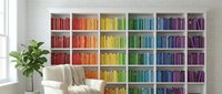 Modern home library with colorful rainbow organized books on white shelves creating vibrant wall display in contemporary living room interior.