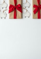 Kraft gift boxes with red ribbon bows and sheep ornaments on white background, perfect for holiday greeting cards, seasonal marketing, and festive packaging design projects.