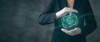 Businessman in suit holding glowing digital brain hologram with protective hands representing artificial intelligence, machine learning and neural network technology.
