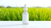 White dropper bottle with pipette on table against blurred green field background for natural skincare cosmetics and organic wellness products.