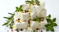 Fresh white cheese cubes with aromatic herbs, rosemary and oregano garnish. Gourmet dairy product for culinary cooking and Mediterranean cuisine recipes.