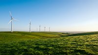 Wind turbines generating clean renewable energy across rolling green hills under clear blue sky for sustainable power production.