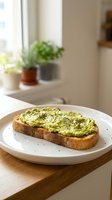 Fresh avocado toast with sesame seeds on sourdough bread served on white plate in bright kitchen with potted plants on windowsill for healthy breakfast concept.