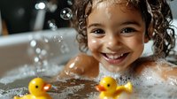 Young mixed race child with curly hair smiling during bath time with yellow rubber ducks, soap bubbles and water splashes creating playful atmosphere.