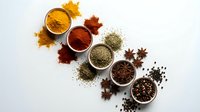 Colorful aromatic spices and seasonings in bowls with scattered powder on white background for culinary cooking and food preparation projects.
