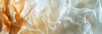 Flowing white and golden silk fabric with soft waves and elegant folds creating luxurious textile background for fashion and design projects.
