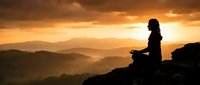 Woman meditating in lotus position on mountain peak at golden sunset with layered hills and dramatic sky. Mindfulness, yoga practice, spiritual wellness concept.