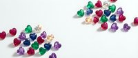 Colorful assorted gemstones scattered on white background featuring emeralds, rubies, sapphires and amethysts for jewelry design and luxury concepts.
