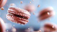 Pink macarons with sparkly sugar crystals floating in air against soft blue background, creating dreamy pastry composition with selective focus.