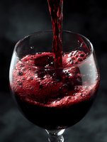 Red wine pouring into glass with splash and bubbles against dark background for luxury dining and beverage concepts.