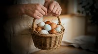 Adult hands holding wicker basket filled with brown and white eggs, suitable for farm, food, agriculture, cooking, and Easter holiday marketing materials.