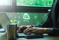 Businessman working on laptop with CO2 reduction digital icons, green energy and carbon footprint concept for sustainability and environment.