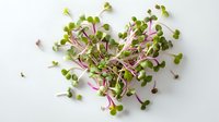 Fresh microgreens with vibrant green leaves and purple stems arranged in heart shape on white background, rich in nutrients for healthy eating.
