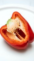 Red bell pepper sliced in half, displaying fresh seeds and inner cavity, isolated on white background for culinary and food design projects.