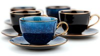 Elegant coffee cups and saucers in deep blue and black with gold trim arranged in artistic composition against white background, showcasing luxury tableware design.