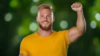 Young Caucasian man in yellow t-shirt celebrating with raised fist against green bokeh background. Happy male showing success gesture and positive emotions.