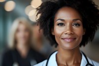 Young African American businesswoman with natural curly hair and confident smile in professional office setting with soft bokeh background lighting effect.