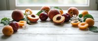 Fresh stone fruits including peaches, plums and apricots arranged on rustic wooden table with natural window light for healthy eating and cooking concepts.