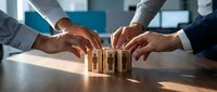 Business team collaboration building wooden blocks together symbolizing teamwork, partnership and corporate strategy development in modern office.