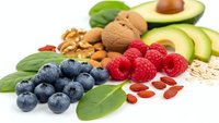 Fresh superfood collection with blueberries, raspberries, avocado, walnuts and goji berries on white background for healthy nutrition and diet concepts.