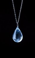 Blue crystal teardrop pendant necklace on silver chain against black background for jewelry design and fashion accessories.