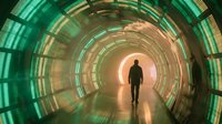Silhouette of person walking through futuristic tunnel with glowing green and orange circular light patterns creating sci-fi corridor atmosphere.